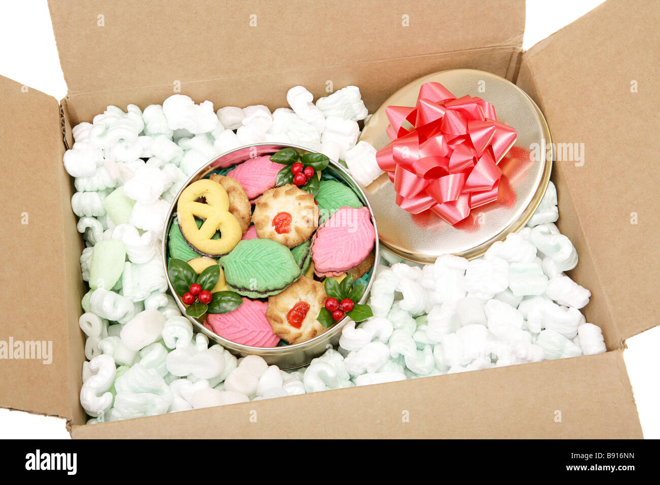 A tin of colorful Christmas cookies packed in peanuts and ready for mailing White background Stock Photo