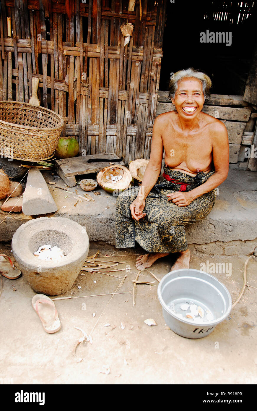 Topless Bali aga old woman with her traditional tool to break coconut  meat,Julah village,Indonesia Stock Photo - Alamy