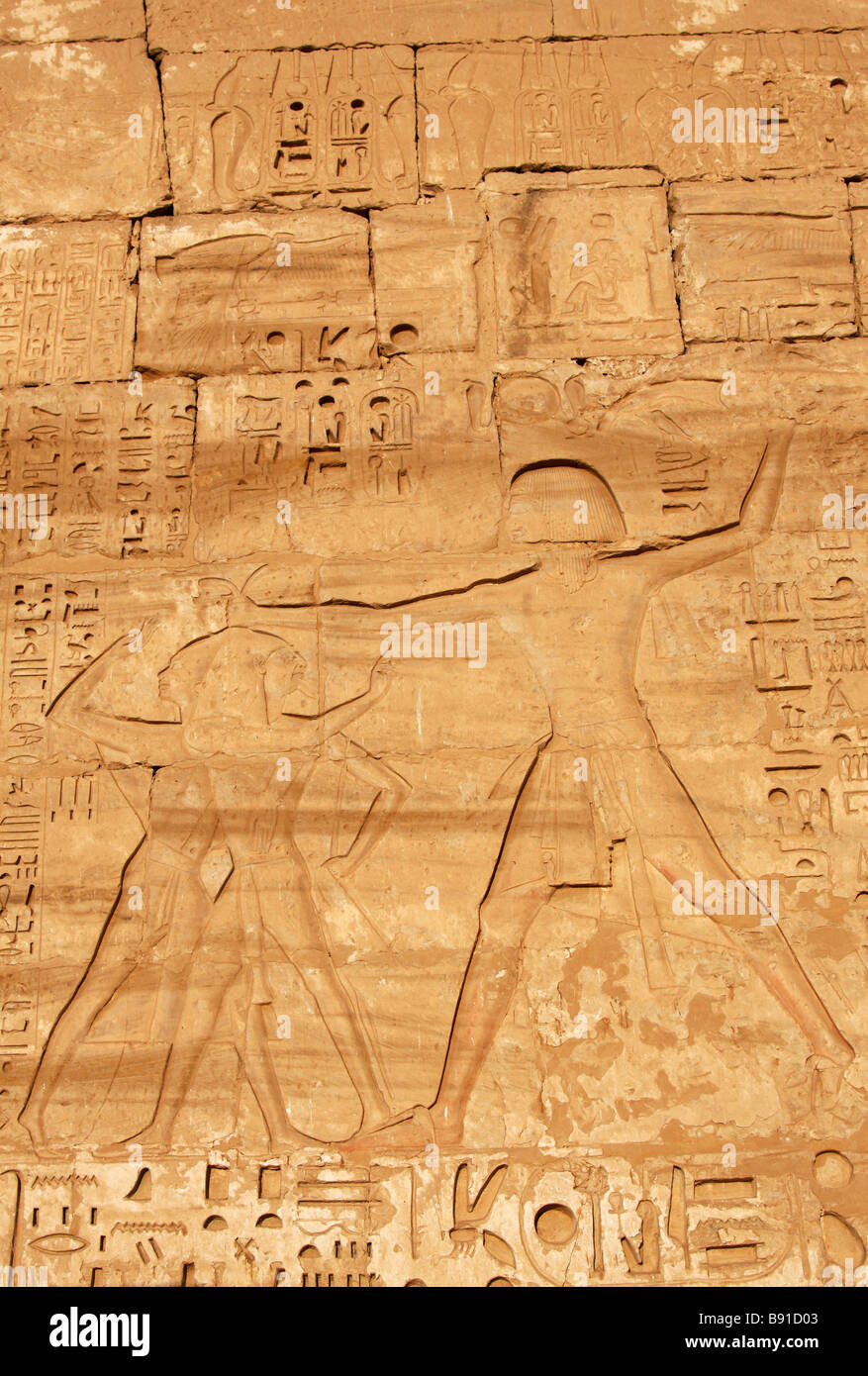 Relief of Pharaoh Ramesses III slaying enemies carved on pylon wall of [Medinet Habu] Mortuary Temple, 'West Bank', Luxor, Egypt Stock Photo