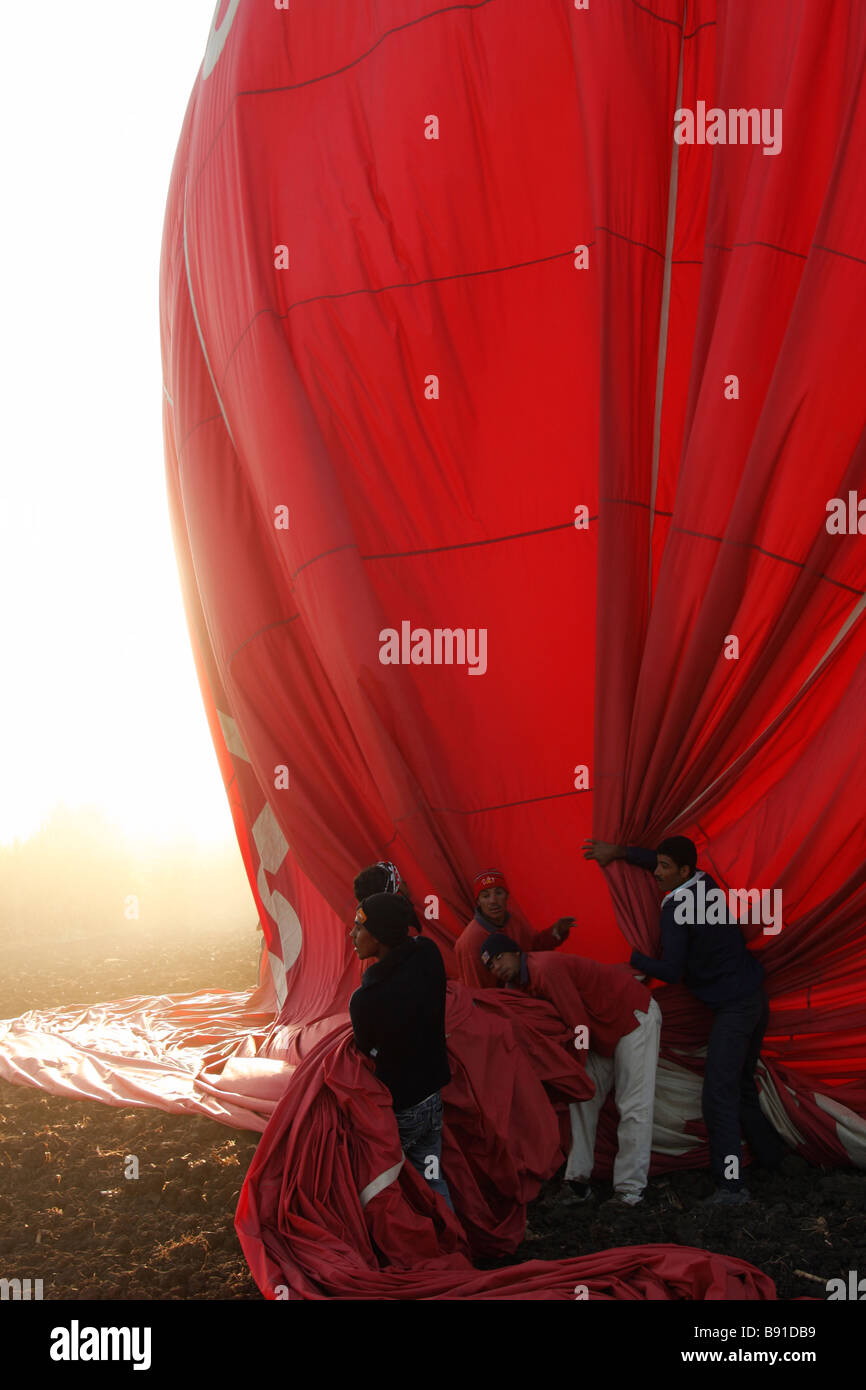Ground crew deflate [hot air balloon] after landing in a field, 'West Bank', Luxor, Egypt Stock Photo