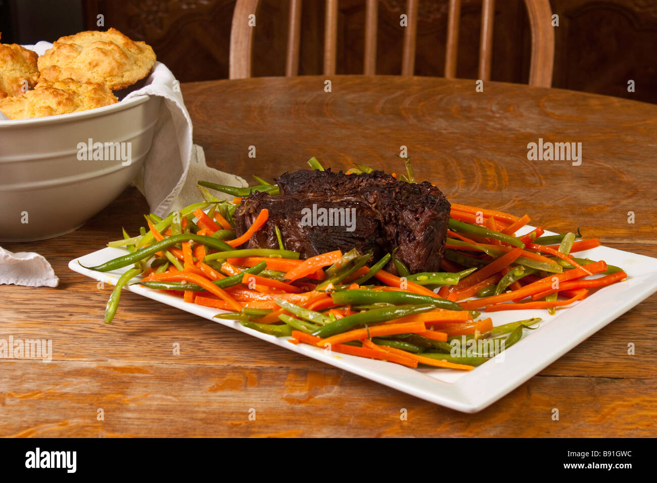 Beef Pot Roast and julienned green beans and carrots  on a white platter Stock Photo