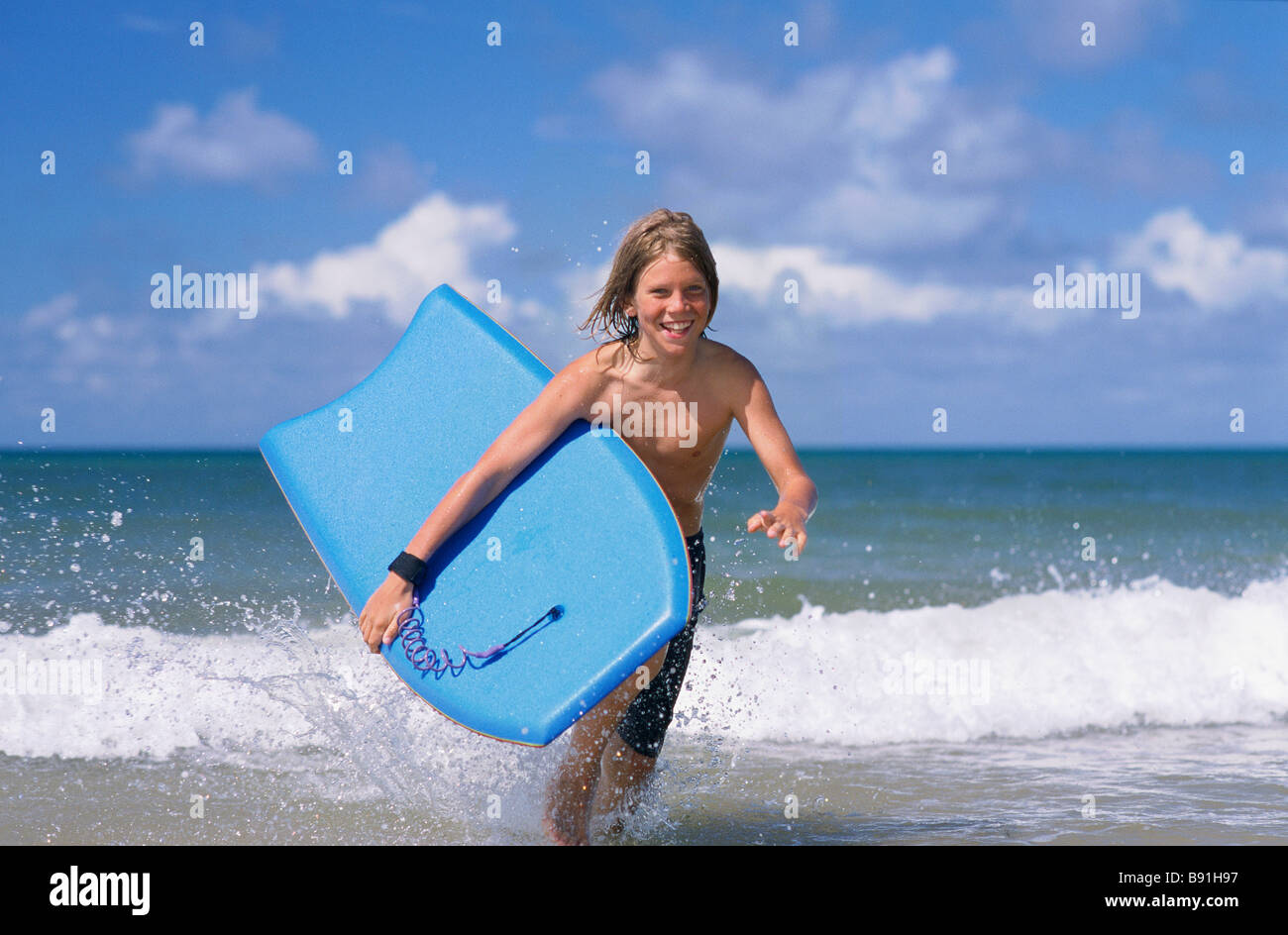 Boy running out of surf with body board Stock Photo - Alamy