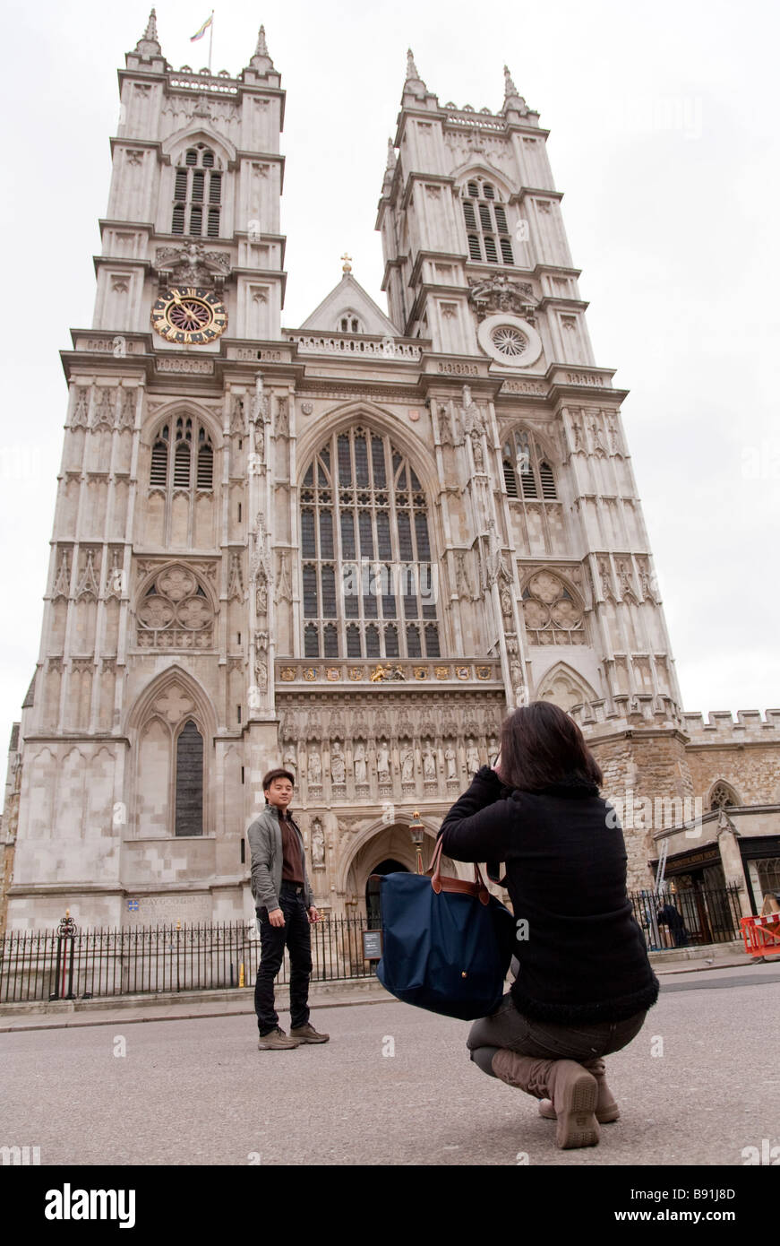 Asian oriental tourist couple in 20s / 30s visiting London, taking photo outside Westminster Abbey Stock Photo