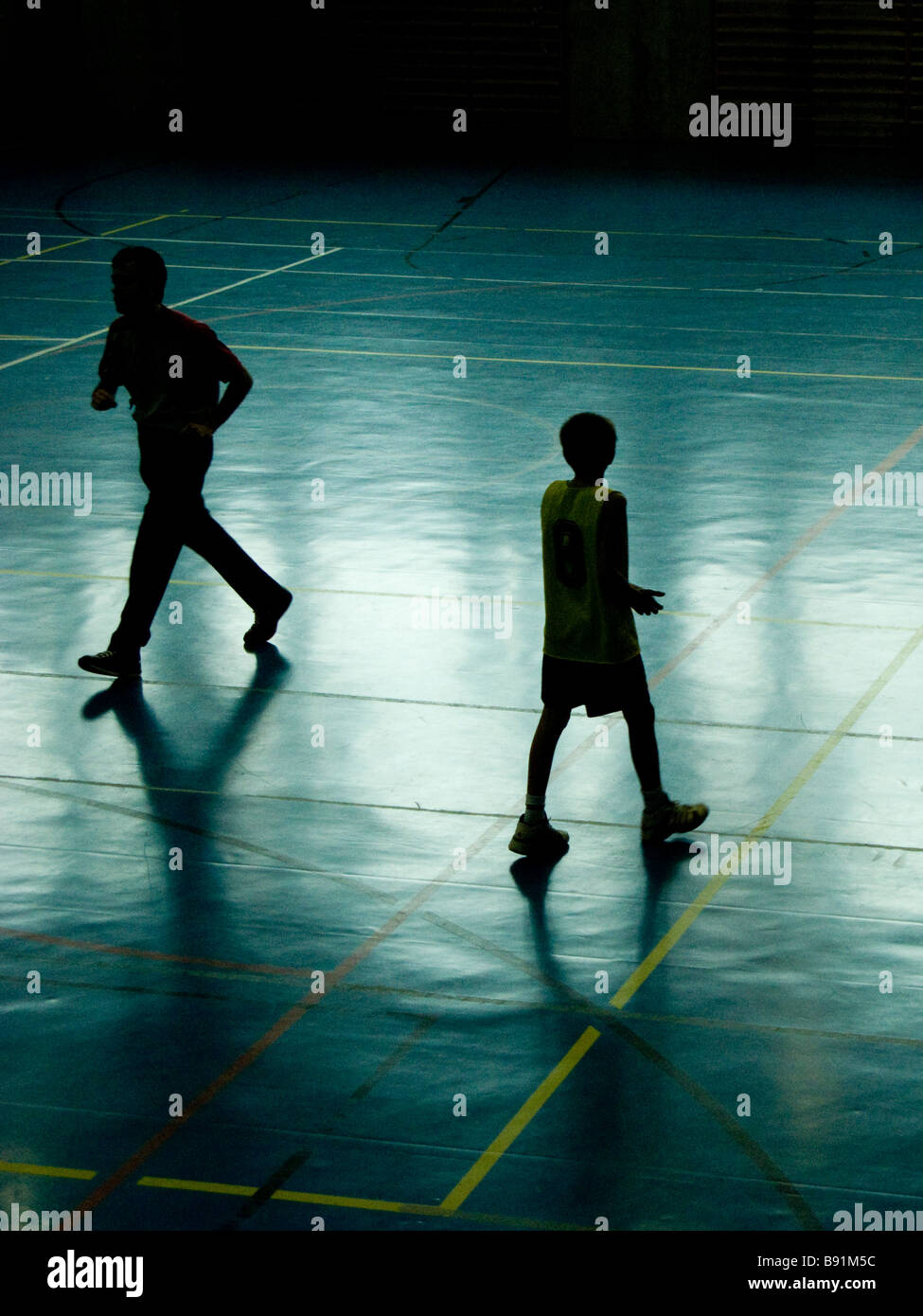 A kid and the referee silhouette during a basketball game. Stock Photo