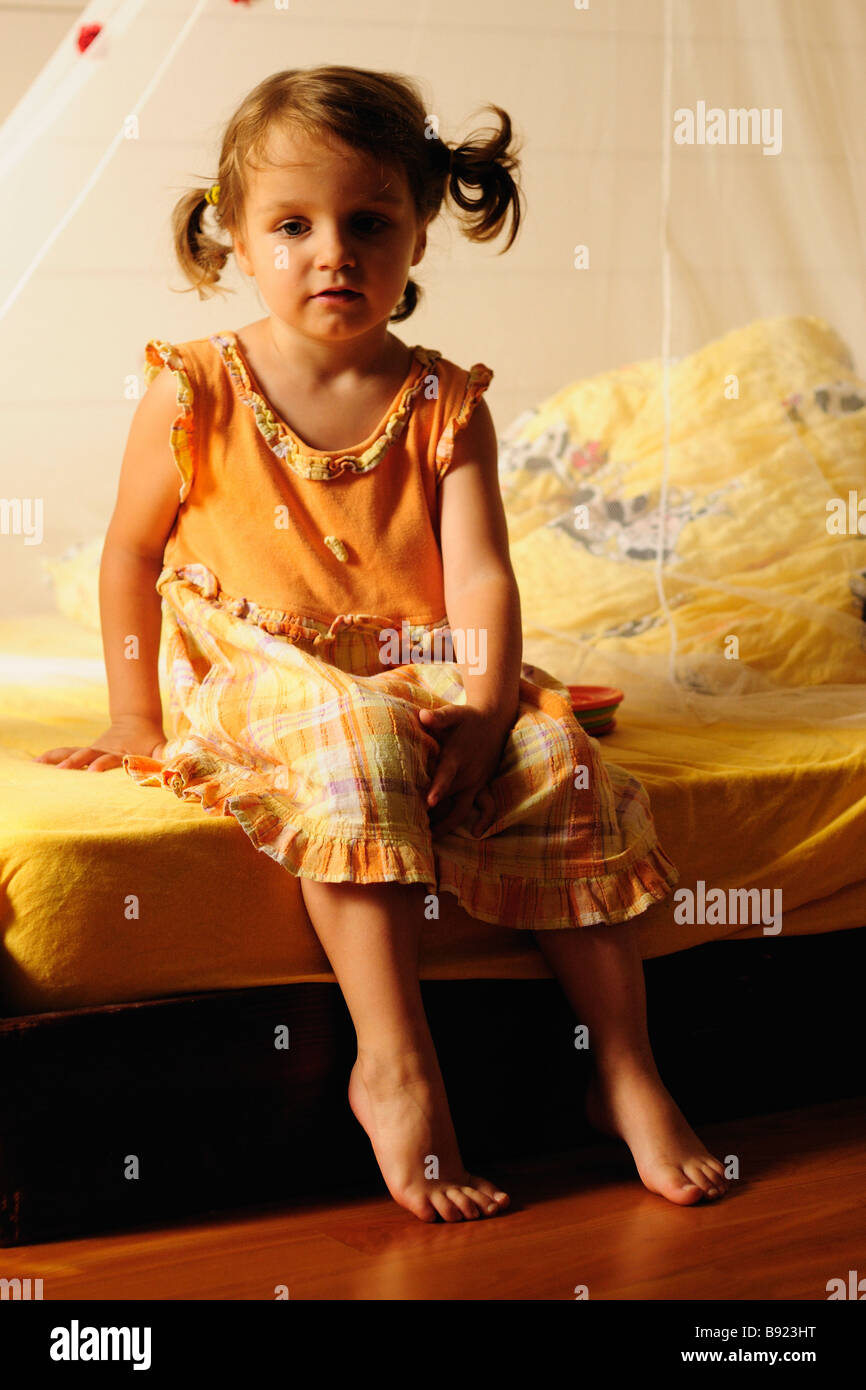 Portrait Of Happy Little Girl Sitting On Bed With Legs Crossed Kid