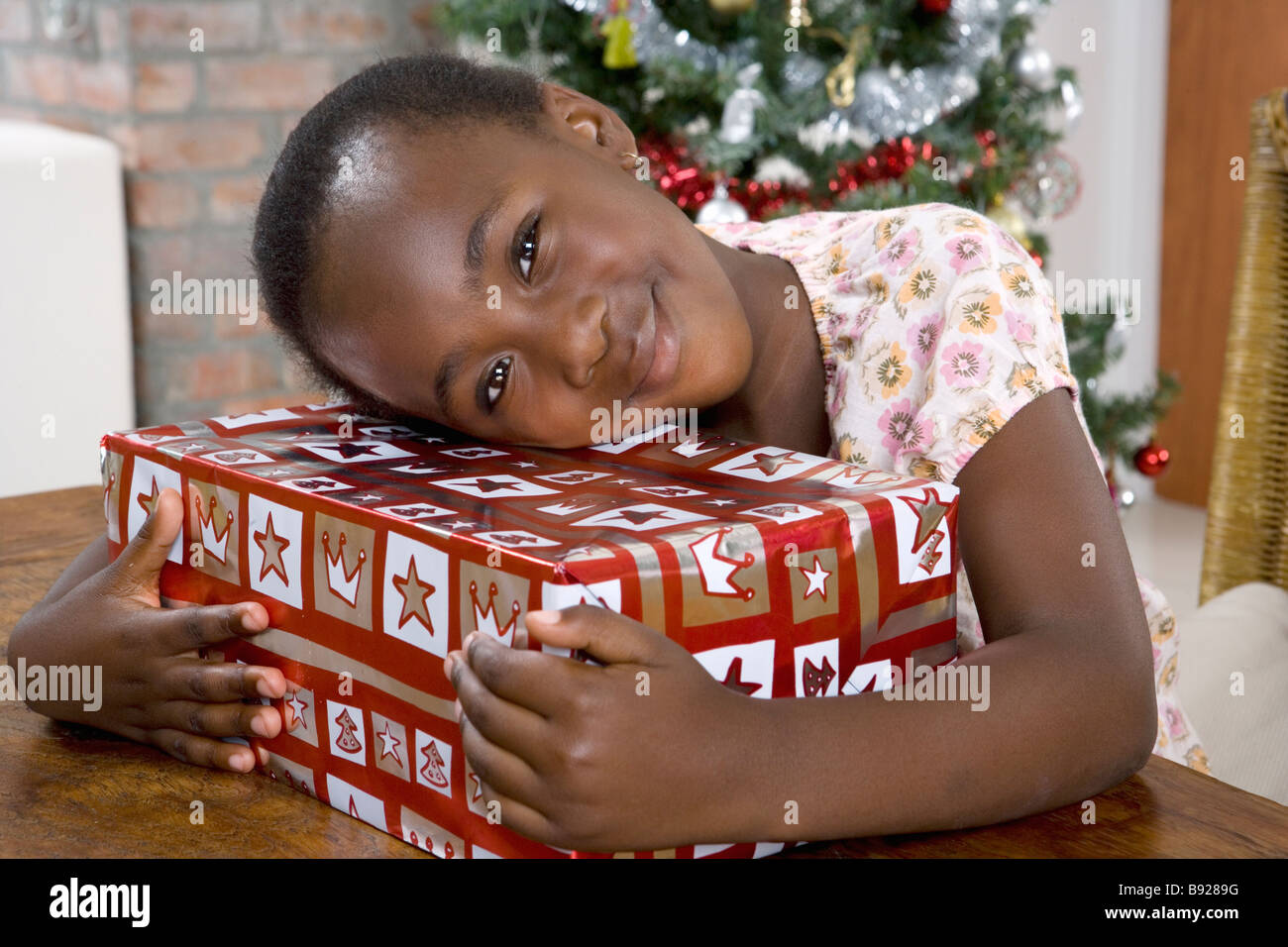 Girl embracing a Christmas present Stock Photo - Alamy