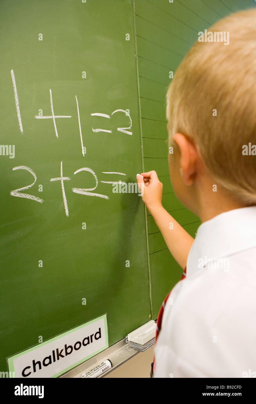 Young Caucasian Boy Writing on a Classroom Blackboard Stock Photo - Alamy