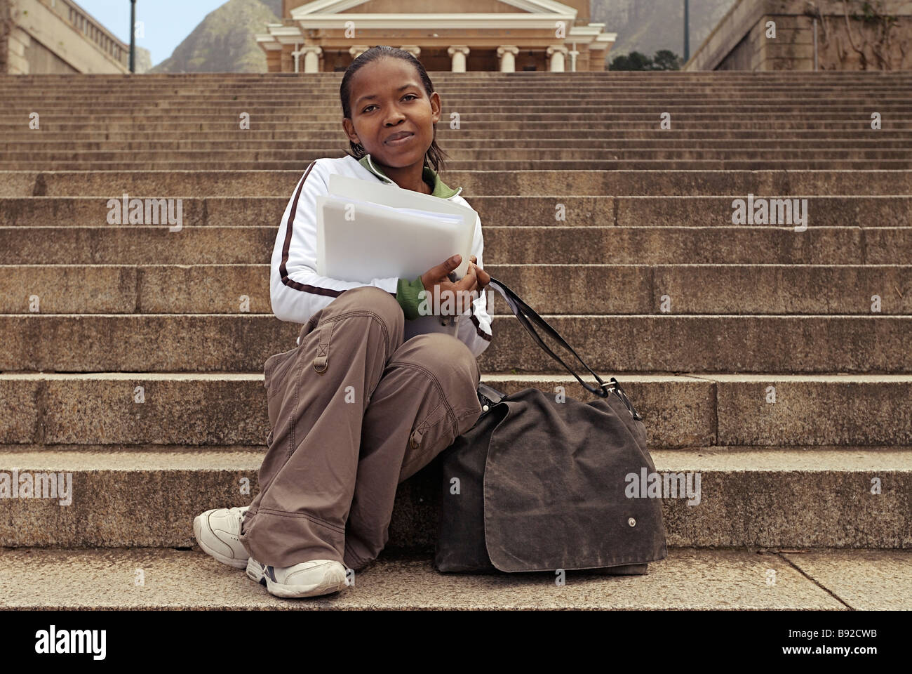 Female student on university steps with file and bag Cape Town Western Cape Province South Africa Stock Photo