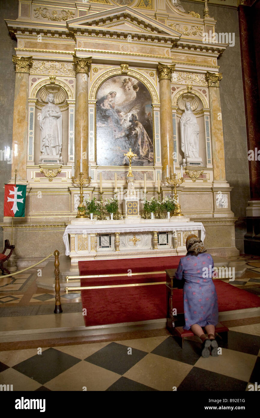 Woman kneeling in prayer beneath a painting by Gyula Benczur in St Stephen s Basilica Szent Istvan Bazilika in Budapest Stock Photo