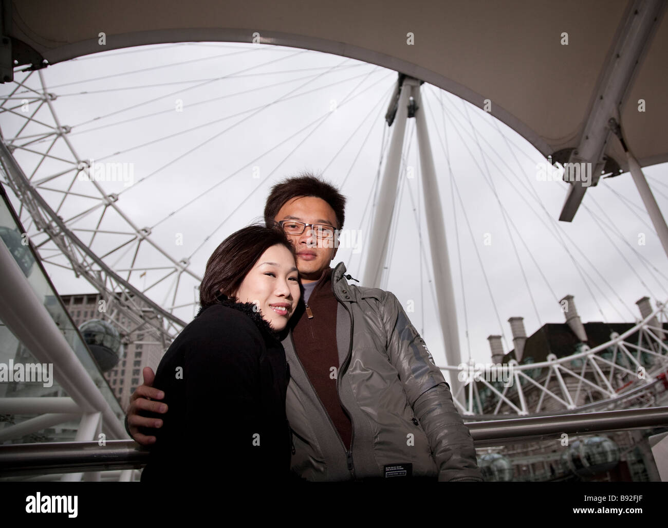 Asian oriental tourist couple in 20s / 30s visiting London, with London Eye in background Stock Photo