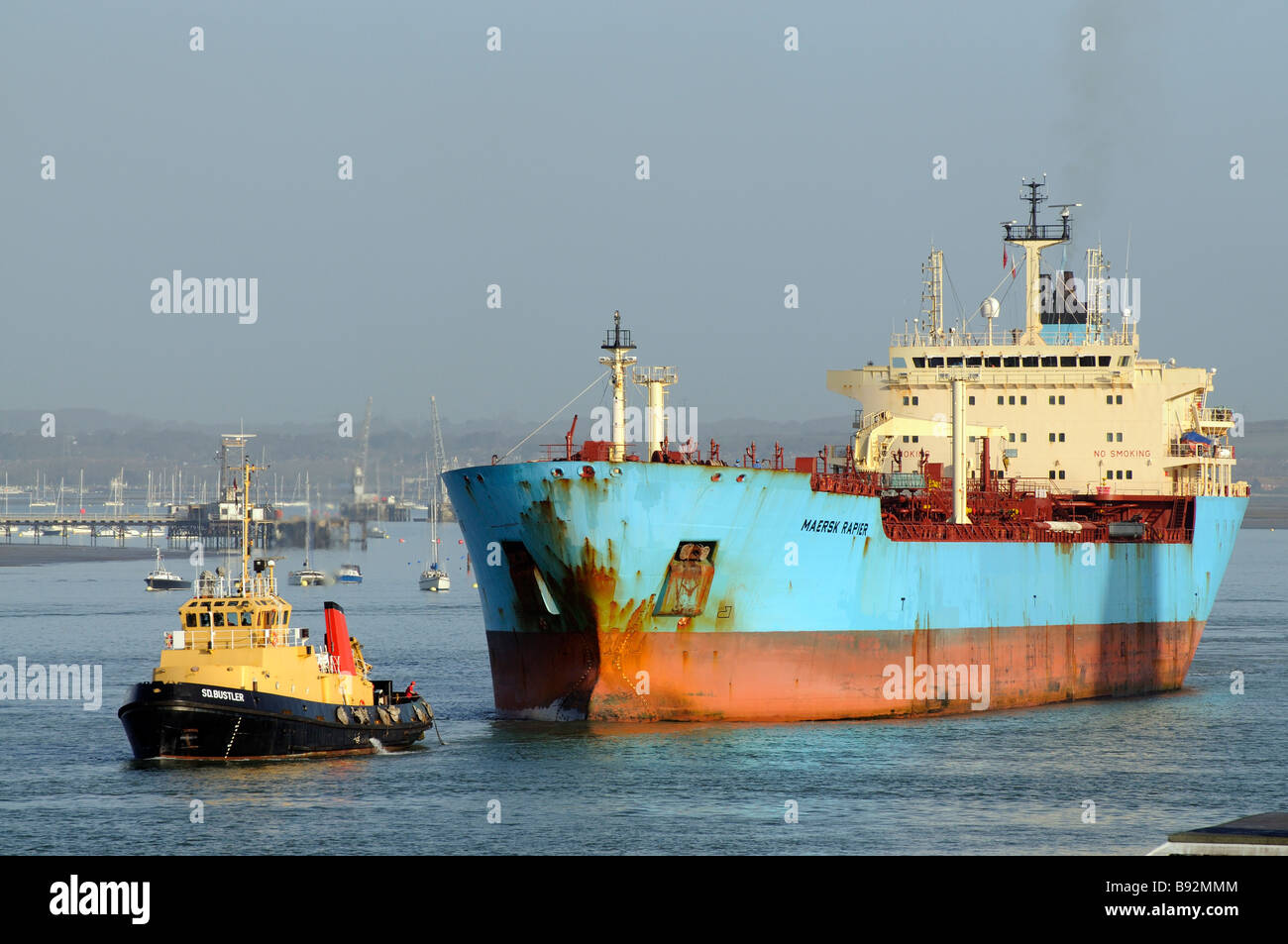 A Serco Denholm SD operated vessel Tug SD Bustler seen escorting the Maersk Rapier tanker ship out of Portsmouth Harbour UK Stock Photo