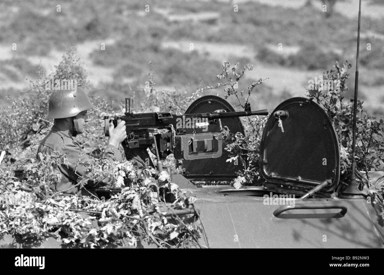 A soldier firing a machine gun from the armoured vehicle Joint military