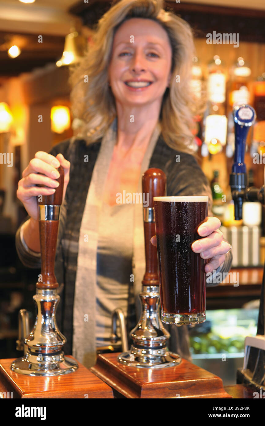 barmaid giving a customer a pint of beer Stock Photo