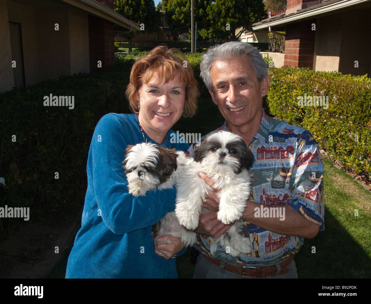 An American couple hold two Shih Tzu puppies in their arms outside a
