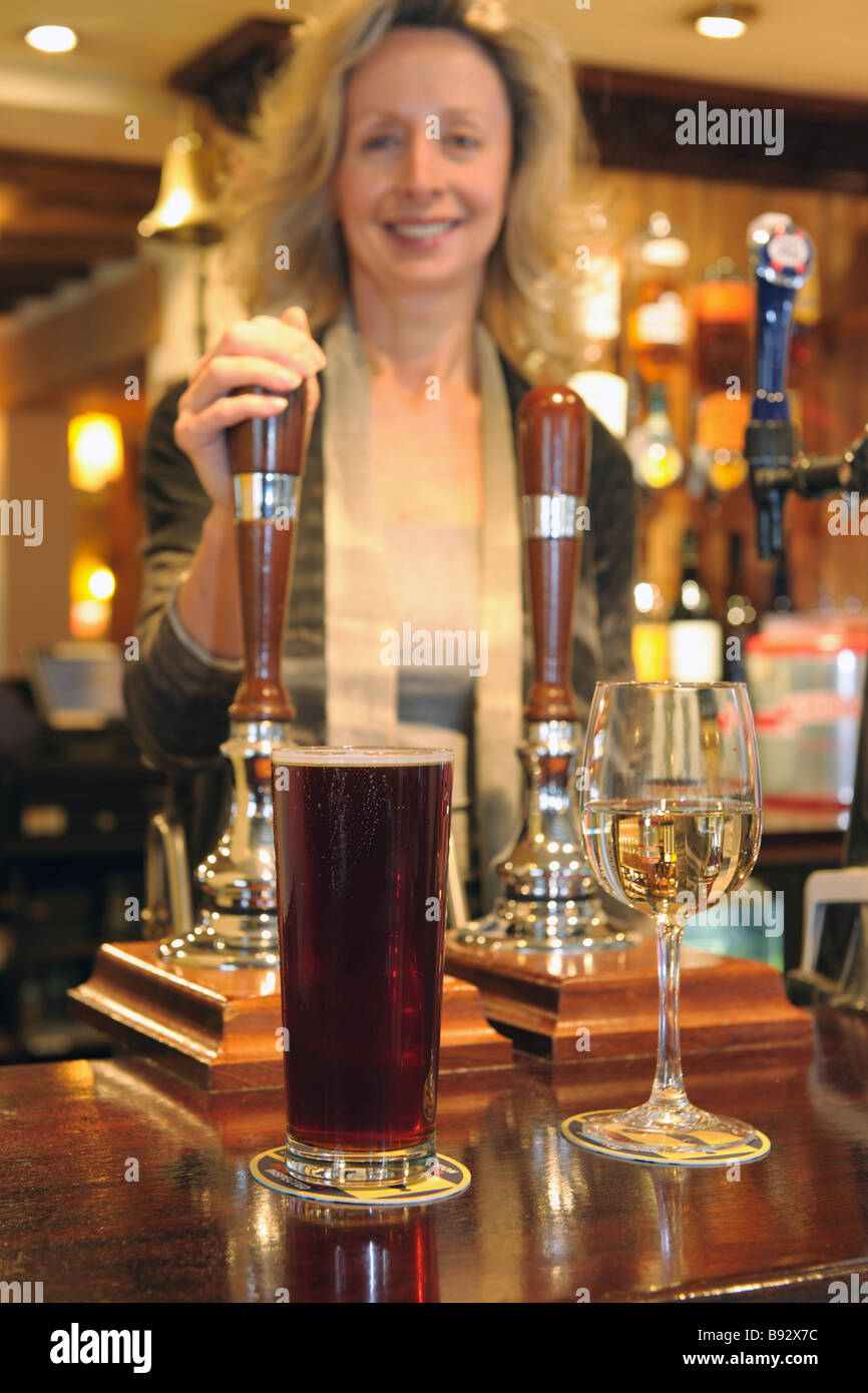landlady standing behind bar with drinks on bar top Stock Photo
