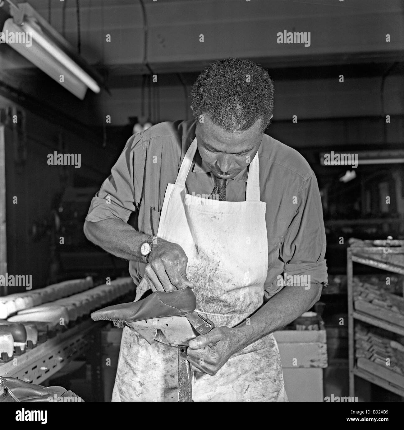 A black worker, part of the 'Windrush generation', working on a moccasin in a shoe factory, Leicester, c. 1959 Stock Photo