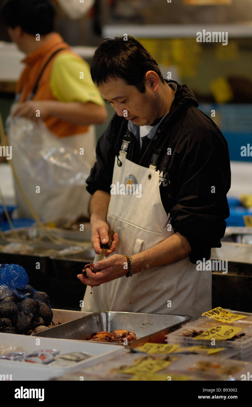 A worker at Tokyo's Tsukiji fish market shelling shellfish Stock Photo ...