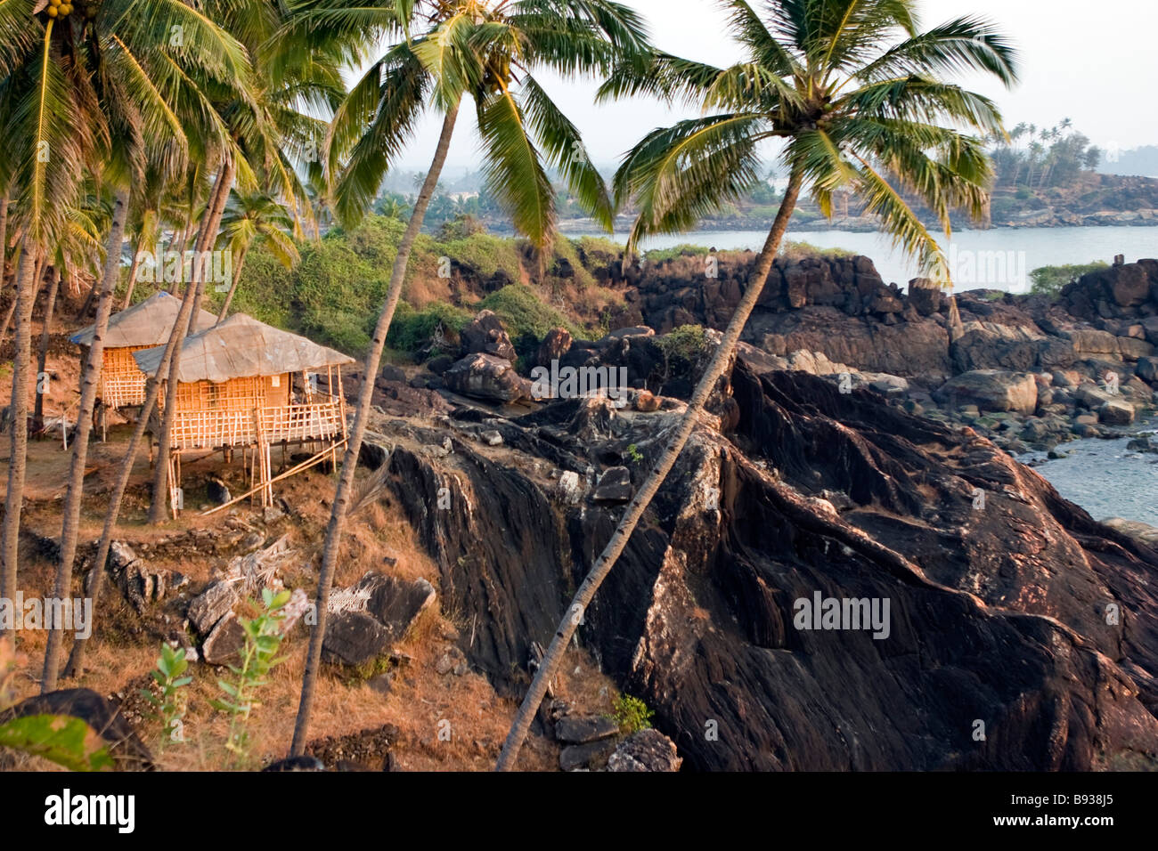 Rocky tropical beach view with huts on sunset. Stock Photo