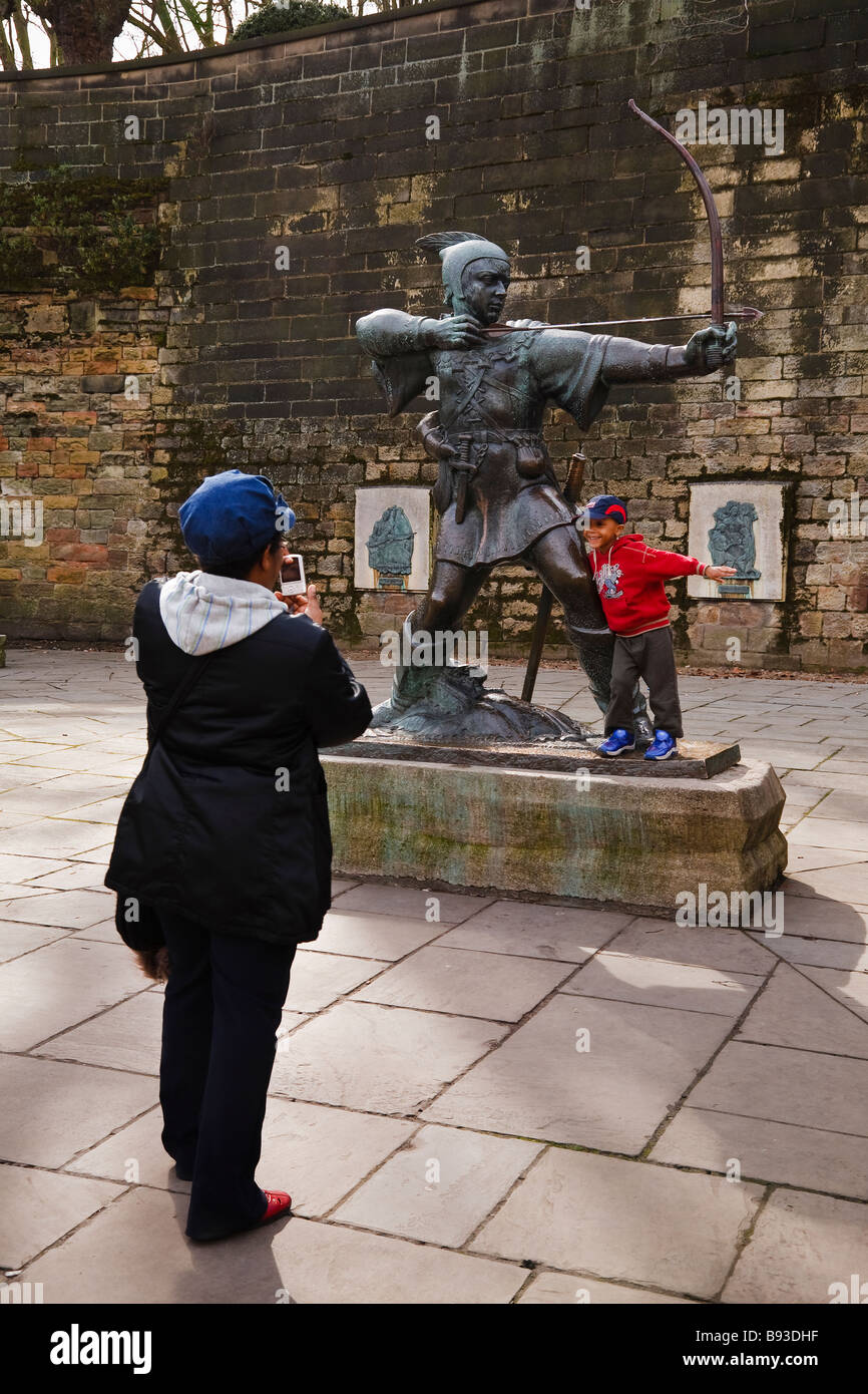 Woman taking a photo of her child playing on the Robin Hood statue outside Nottingham Castle, Nottingham, England, UK Stock Photo