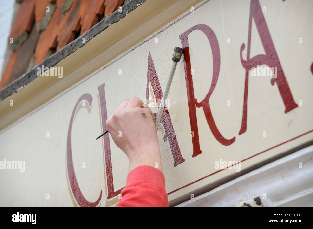 Sign painter Keith Pettit with a mahl stick at work on a shop sign in