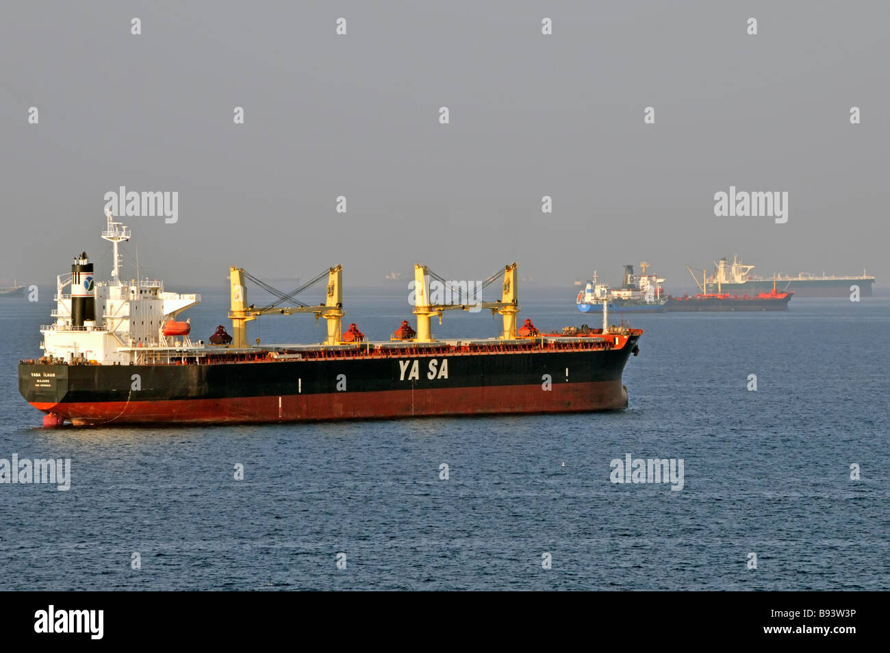 Unladen shipping in heat haze bulk carriers & oil tankers coastal waters anchorage off UAE Fujairah bunkering port Gulf of Oman near Straits of Hormuz Stock Photo