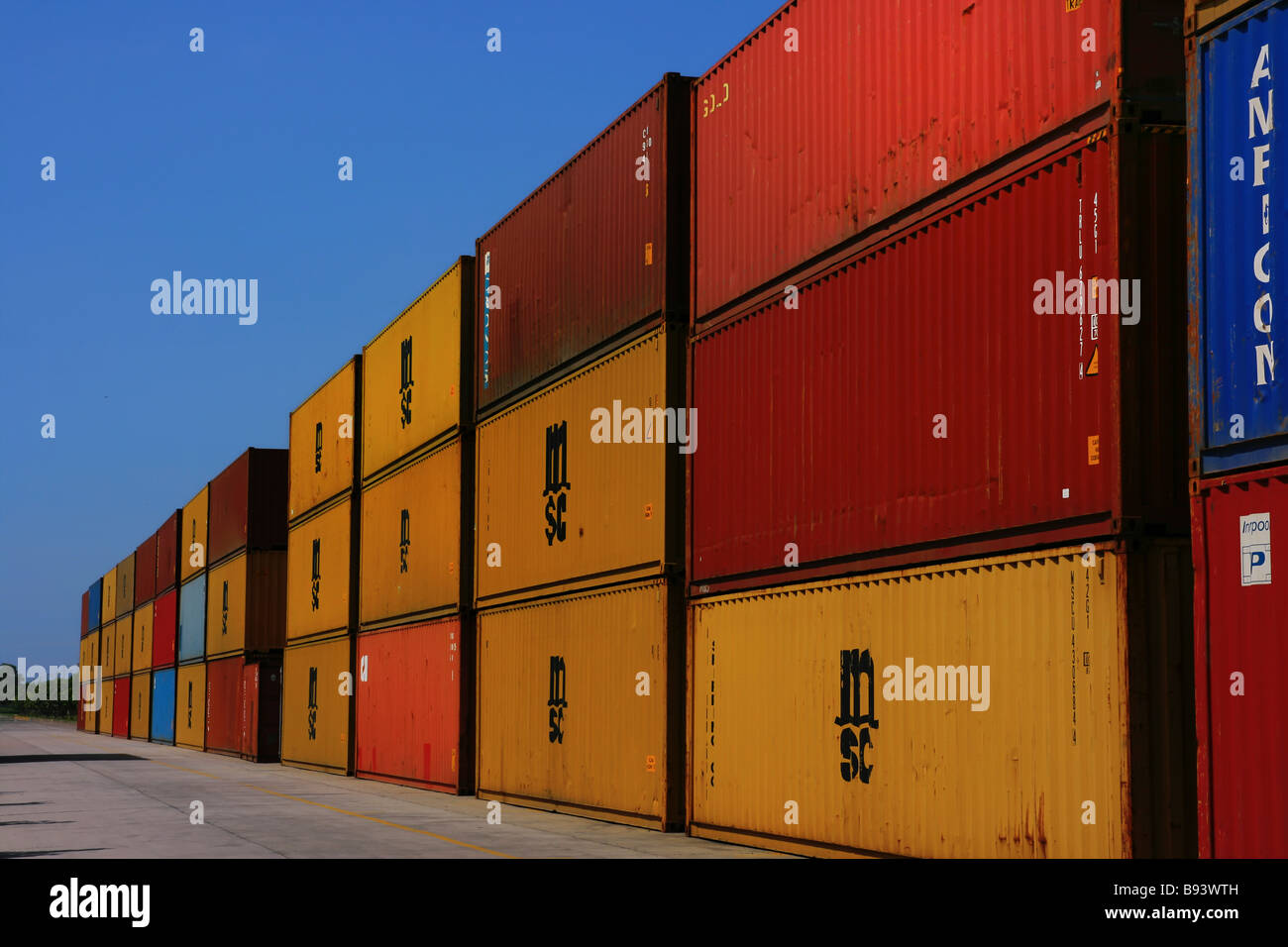 stack of containers in a long road with blue sky background Stock Photo