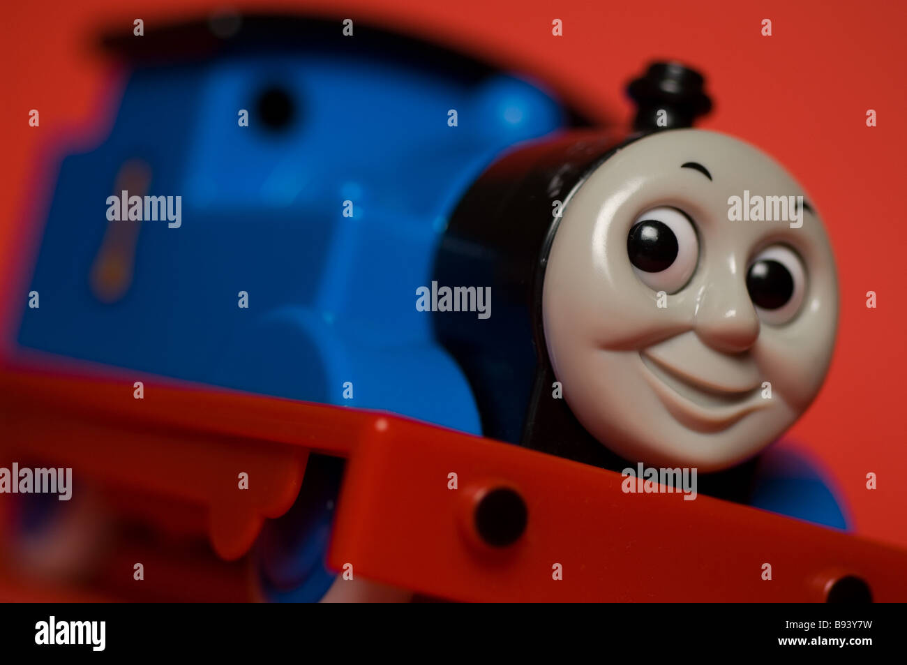 A close up of a child's toy 'Thomas the Tank Engine' on a red background. Stock Photo