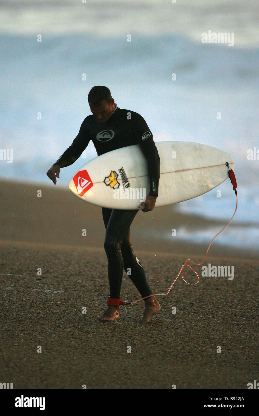 A Surfer walking up the beach with his surfboard Stock Photo - Alamy
