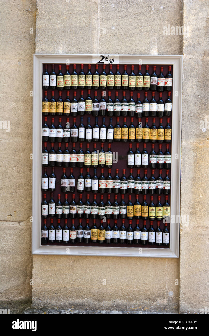 A small wall sign with mini miniature bottles of wine on a wall in St Emilion Bordeaux France Stock Photo