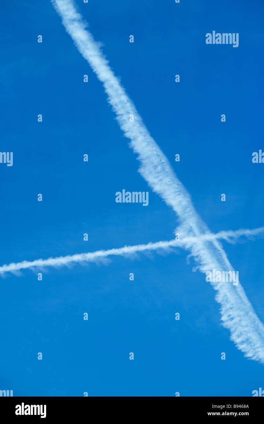 Blue sky with contrails from crossing jet planes Stock Photo