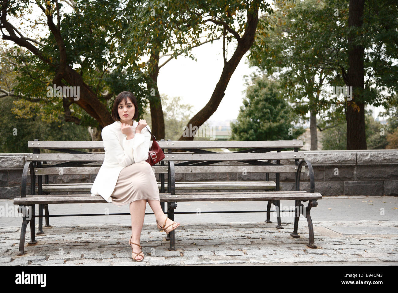 Woman sitting on park bench in city park Stock Photo - Alamy