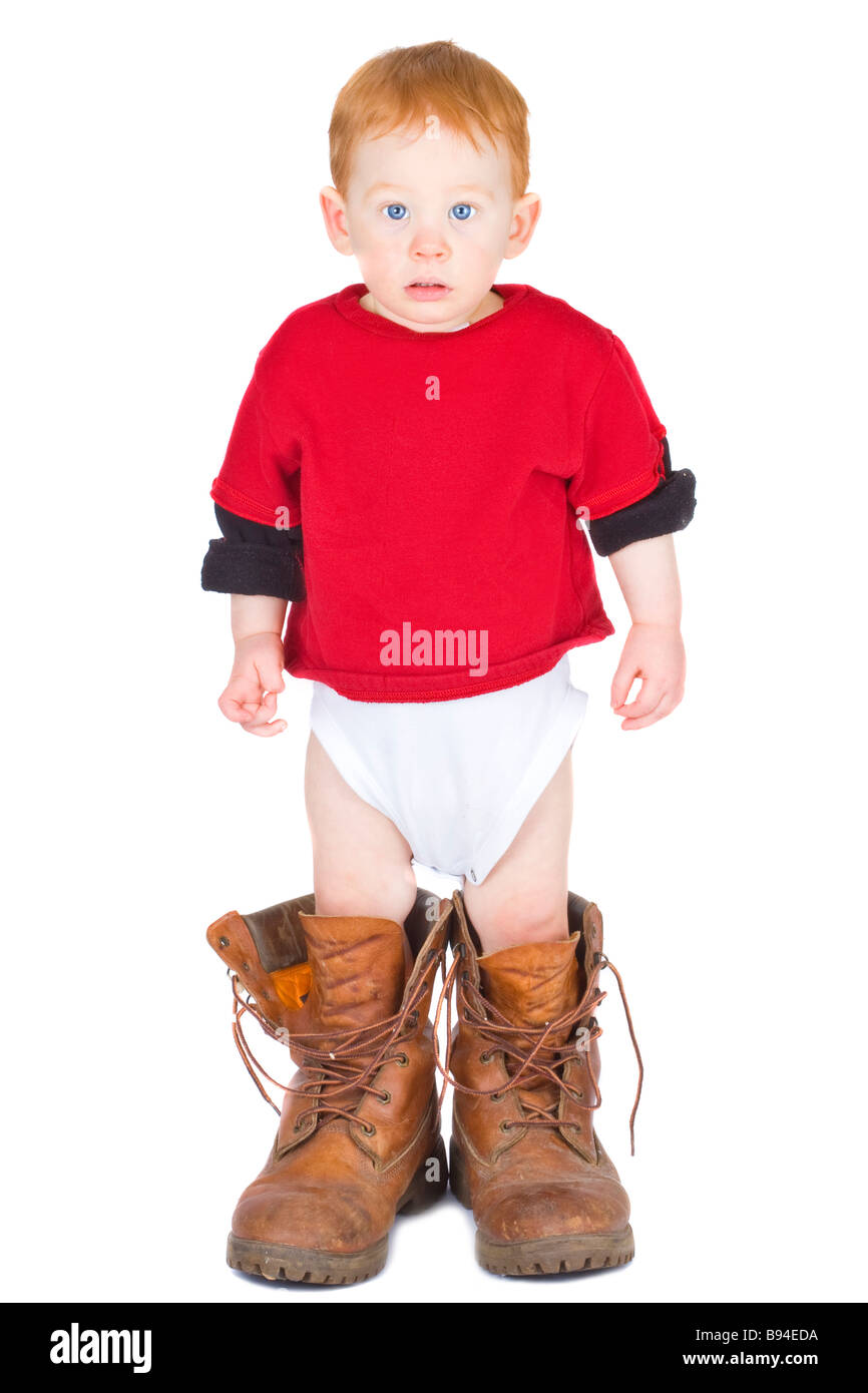 Baby boy standing in an adult pair of work boots Stock Photo