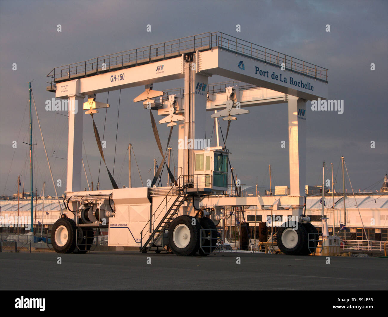 A heavy lift crane in the sea port of La Rochelle for lifting containers from boats and lifting boats seen at sunset Stock Photo