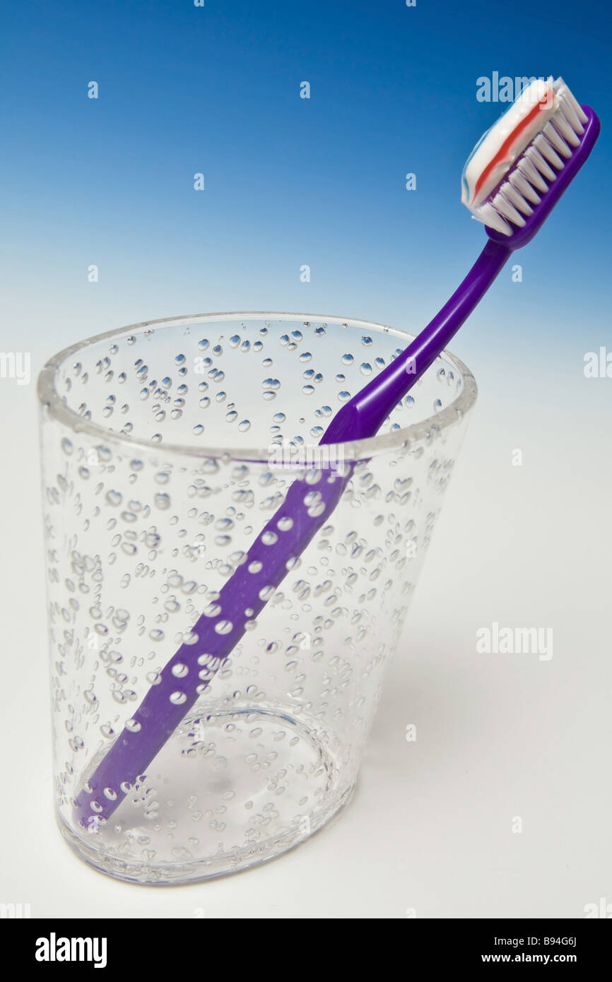 toothbrush and toothpaste in a cup photographed on a graduated blue