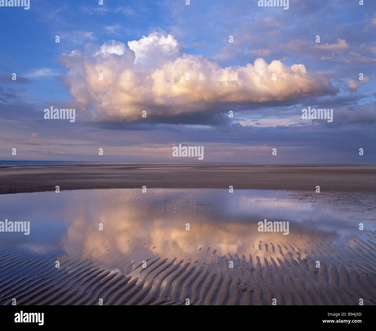 cloud over tidal pool on beach at Holkham Bay on the North Norfolk coast UK Stock Photo