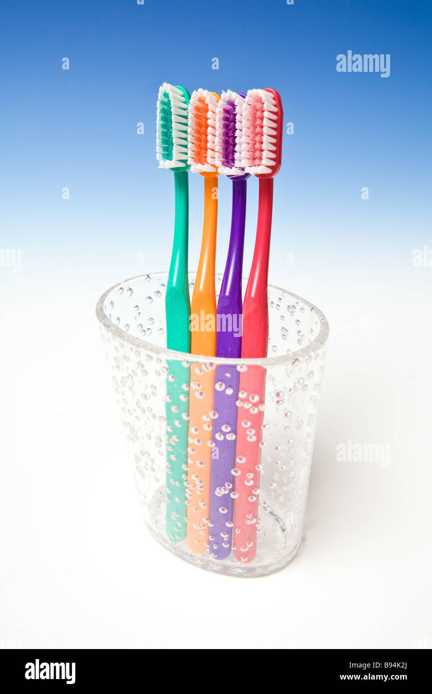 Colored tooth brushes in a cup on a blue studio background Stock Photo