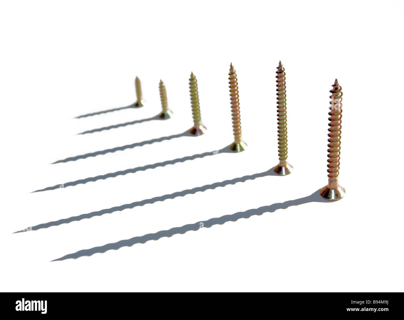A line of receding screws and their shadows. Stock Photo