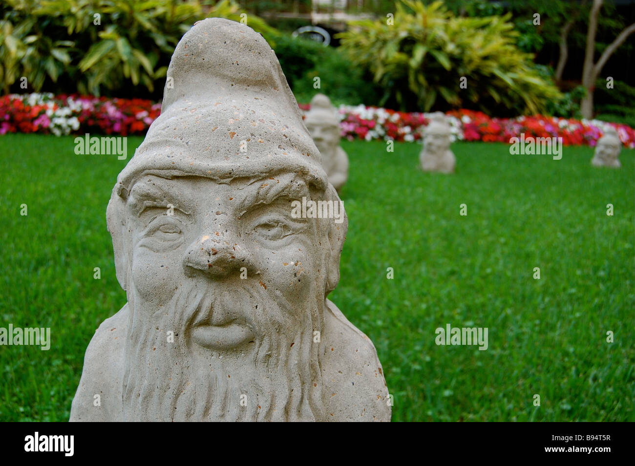 Closeup of garden gnome statue with smaller garden gnomes in the