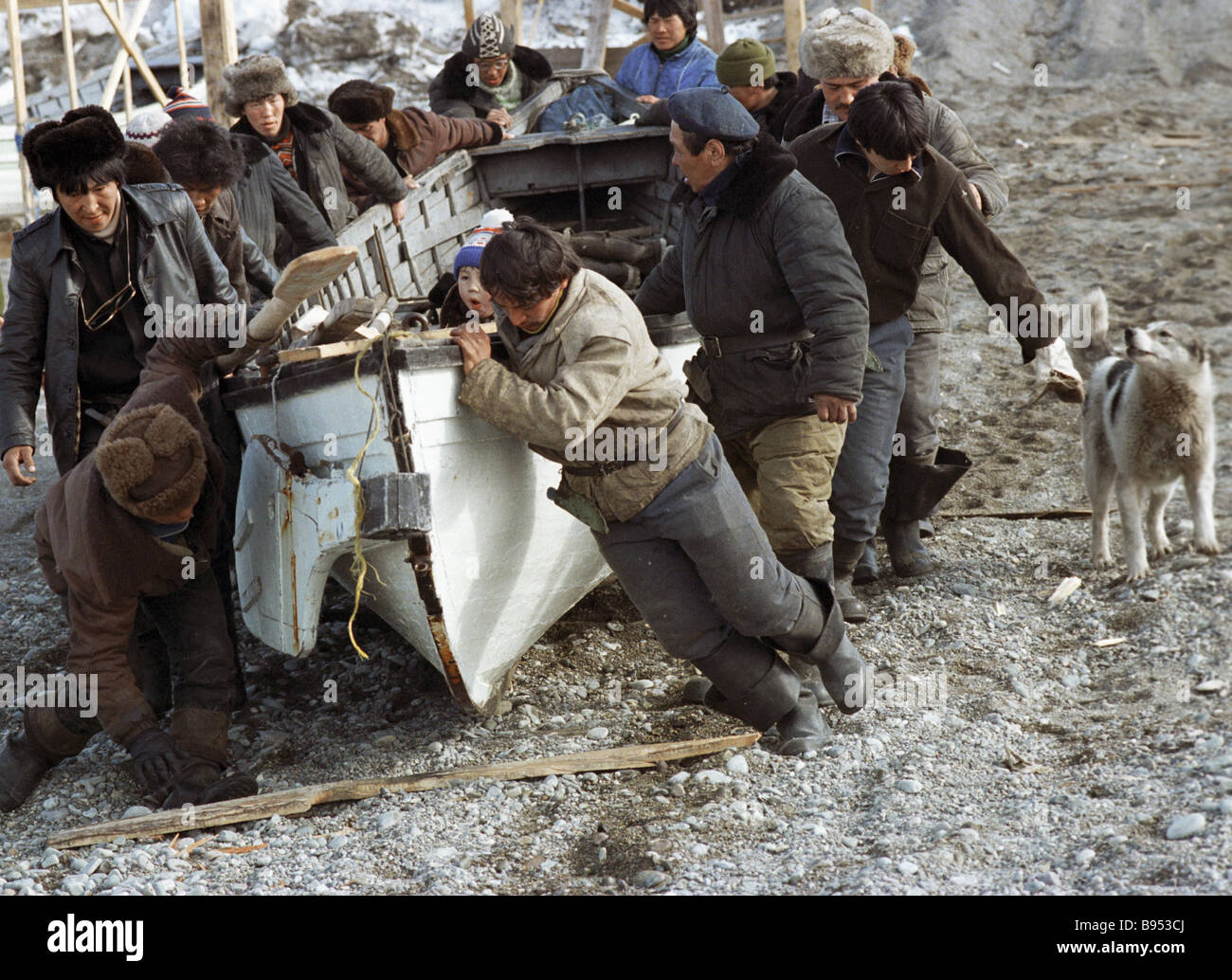 Local residents haul boat to the sea before hunting sea animals Stock