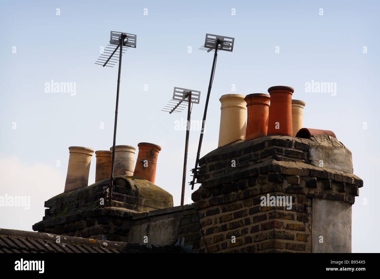 Television Ariels on top of chimneys on a blue sky. Stock Photo