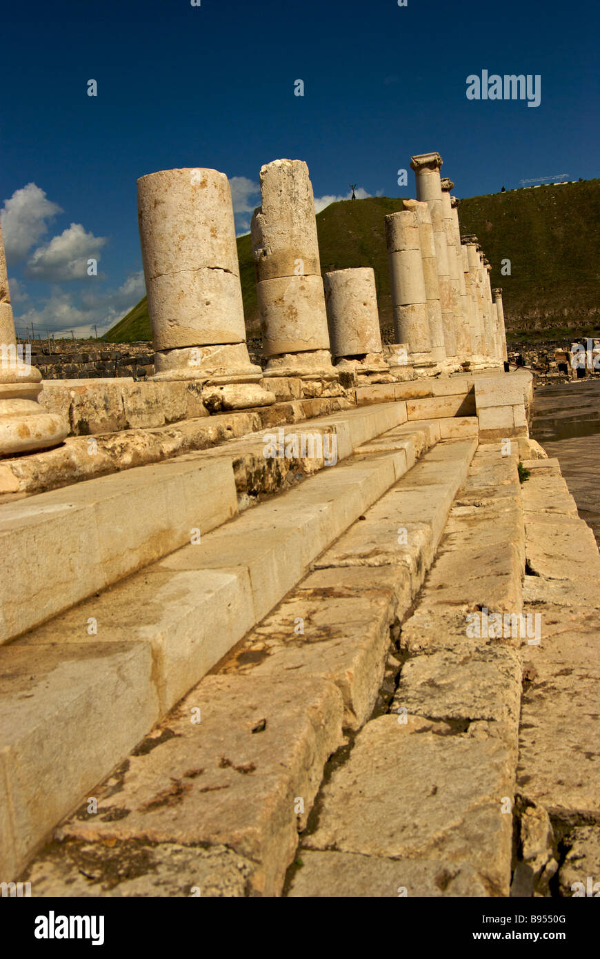 Marble colonnades line Palladius Street from ancient Roman Byzantine period city Scythopolis with great tell in background Stock Photo