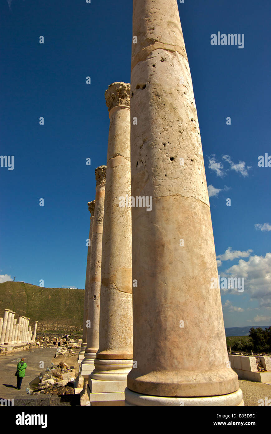 Marble roof support colonnades of Byzantine agora line Palladius Street in Scythopolis with great tell in background Stock Photo