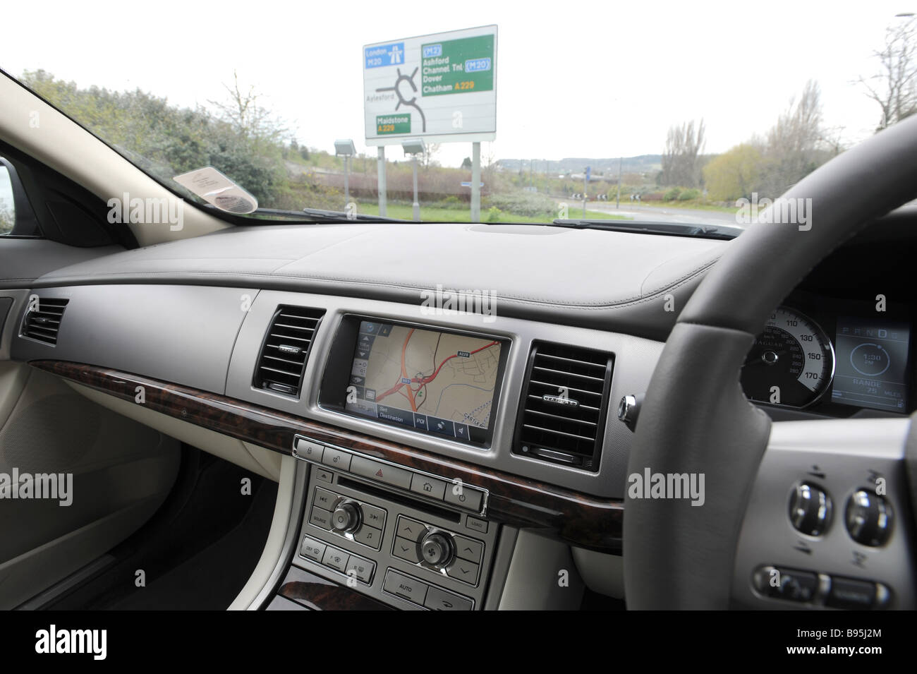 Satellite navigation in a car dashboard Jaguar XF with road sign in