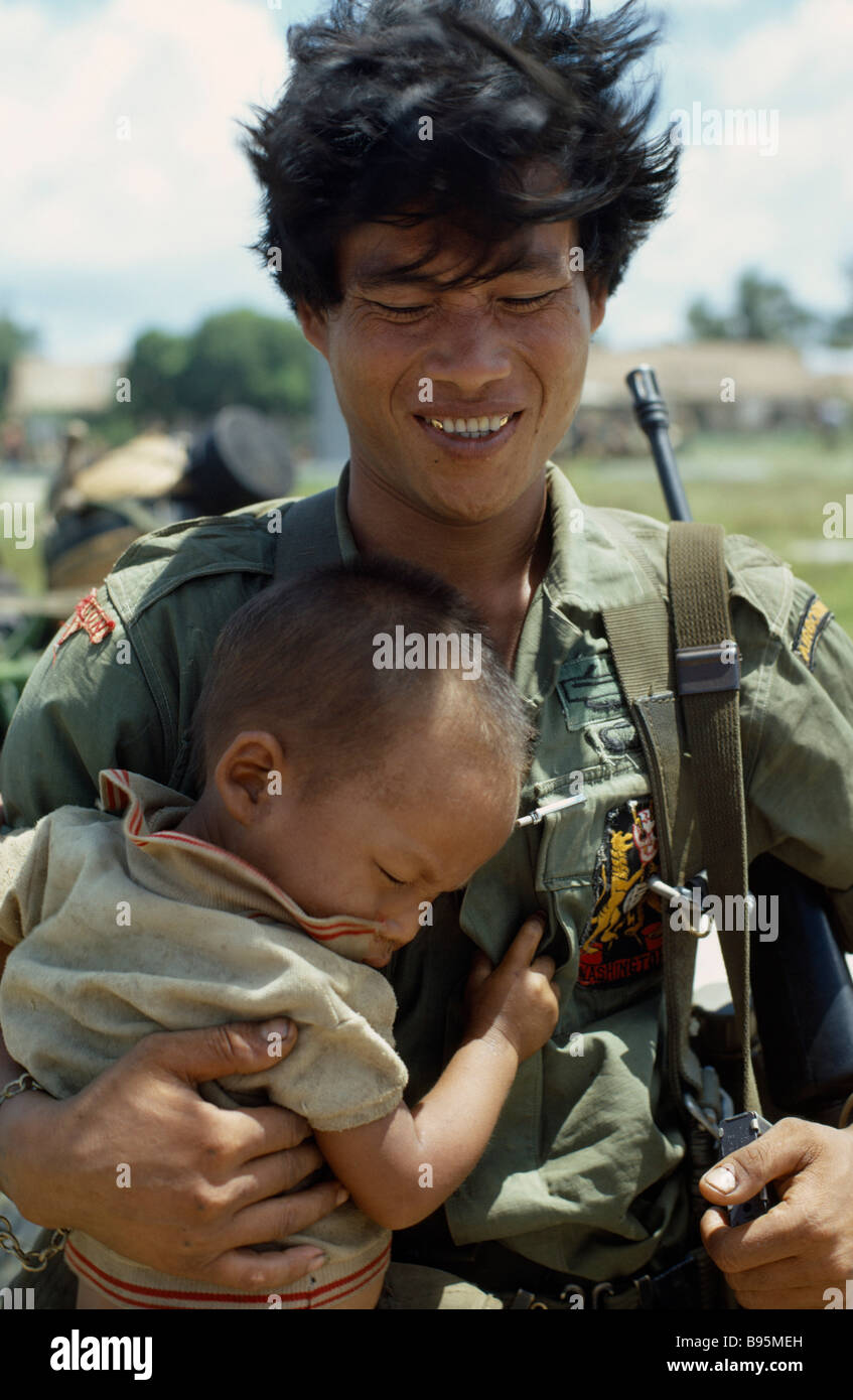 VIETNAM War Central Highlands Siege of Kontum Montagnard soldier carrying young child Stock Photo