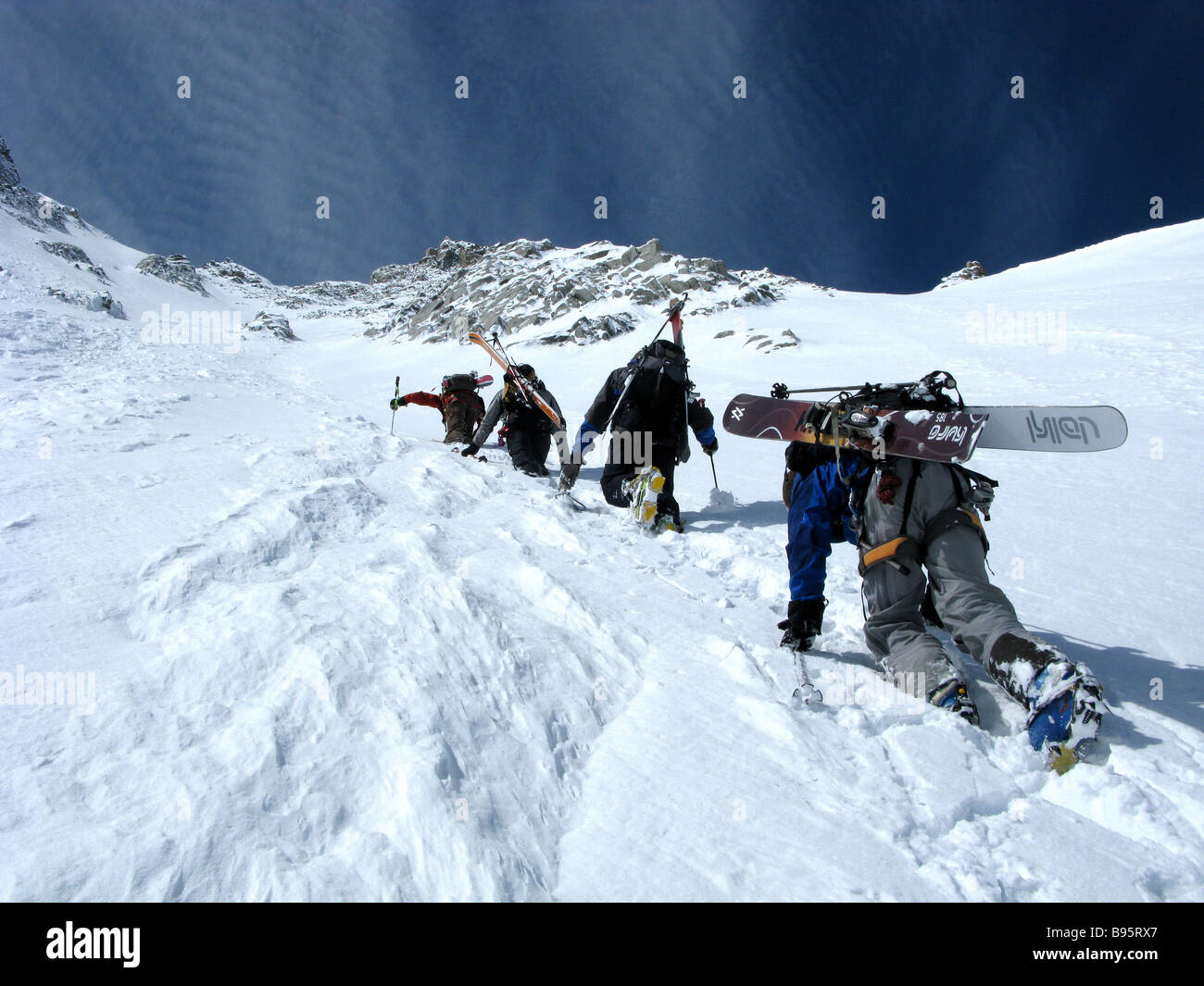 Skiers and snowboarders climbing steep couloir chamonix on a spring ski touring trip Stock Photo