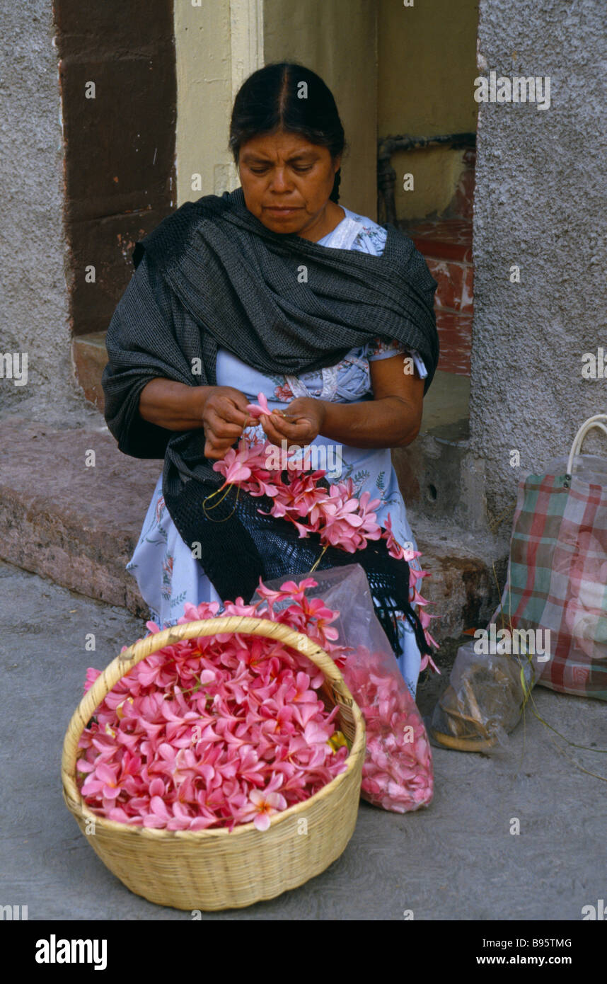 MEXICO Guerrero Woman flower seller sitting on step in street threading