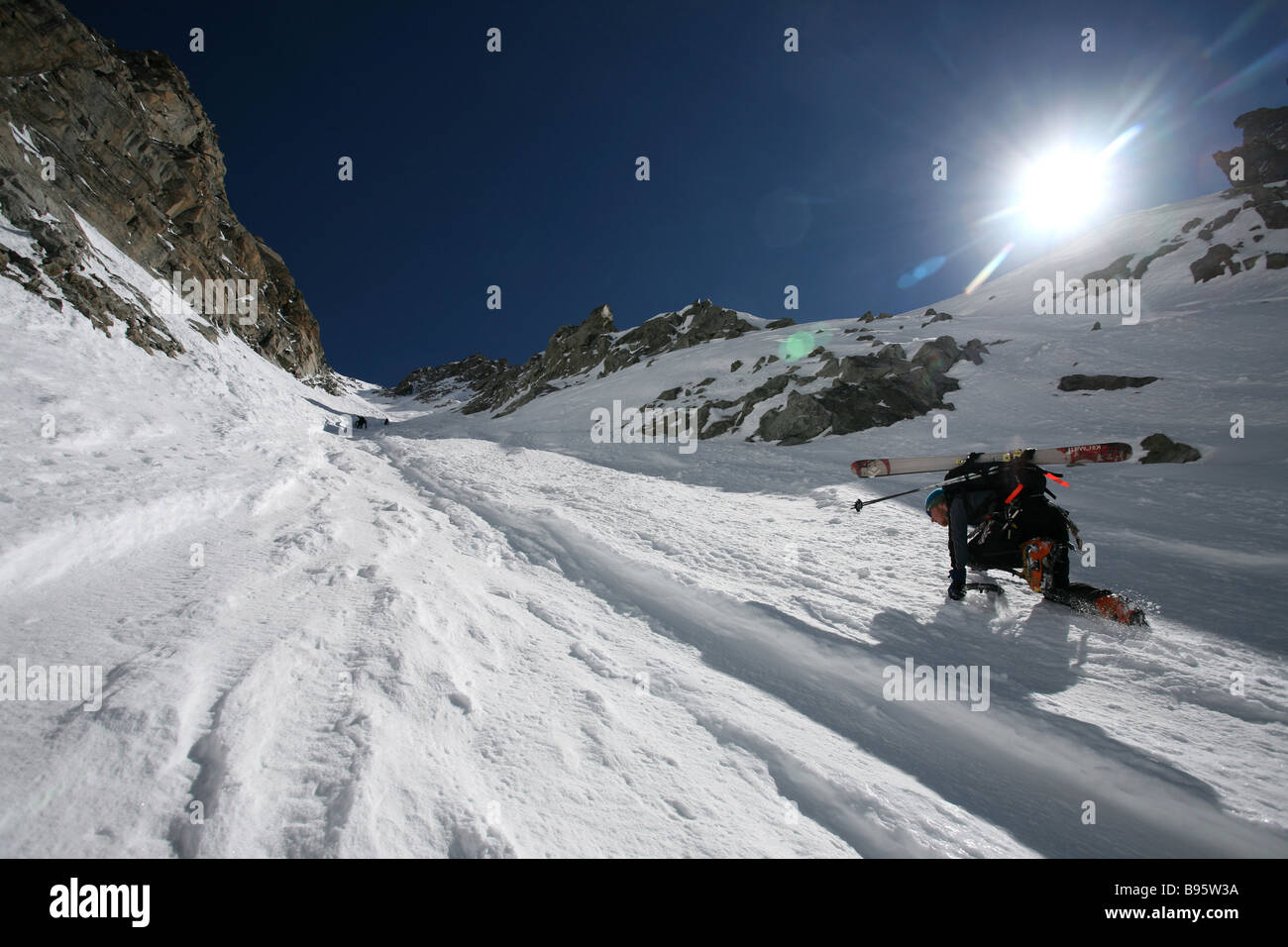 Ski tourers climbing on hands and knees a steep couloir Chamonix France Stock Photo