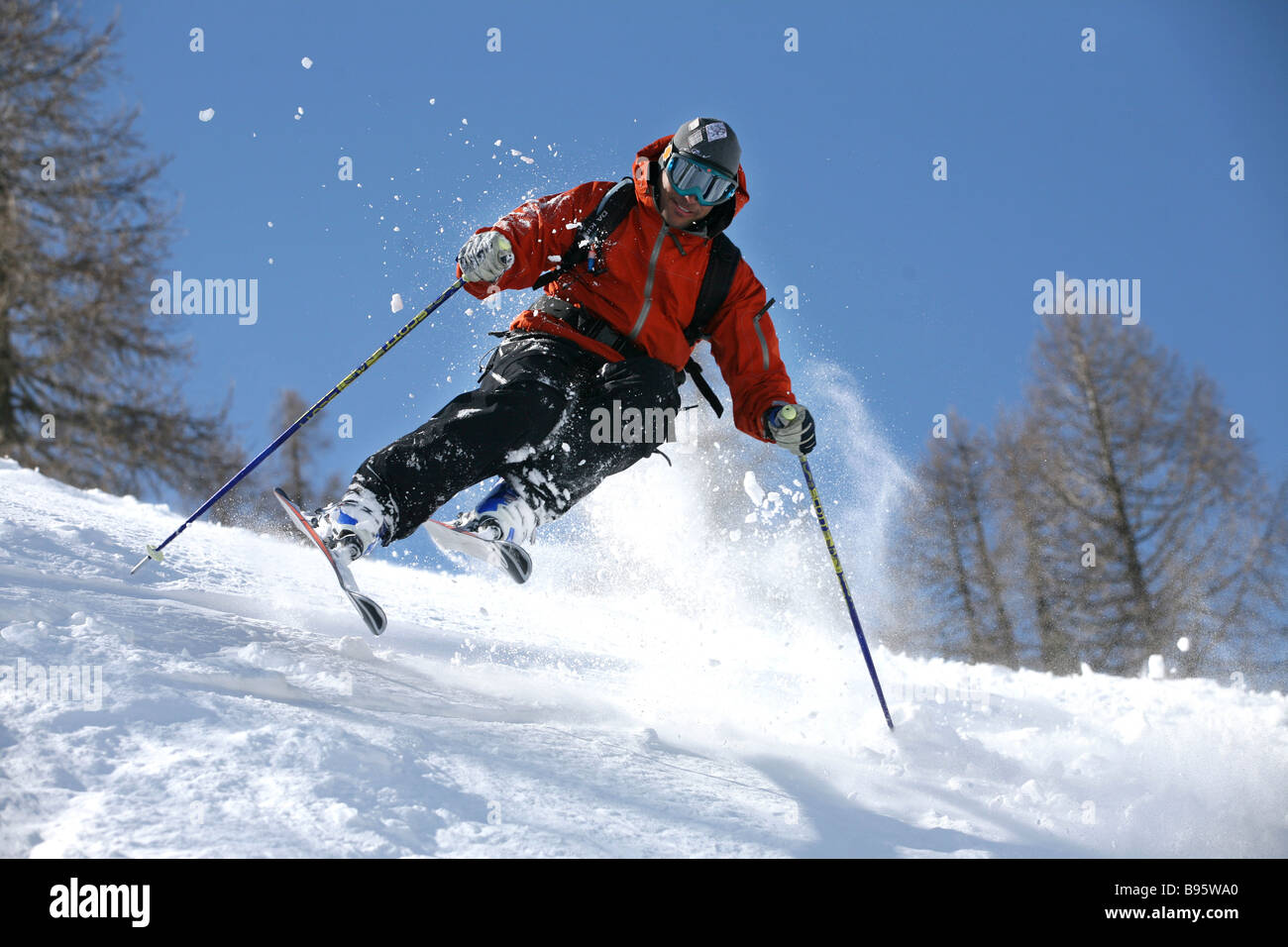 Male skier in red jacket hitting the powder snow Stock Photo