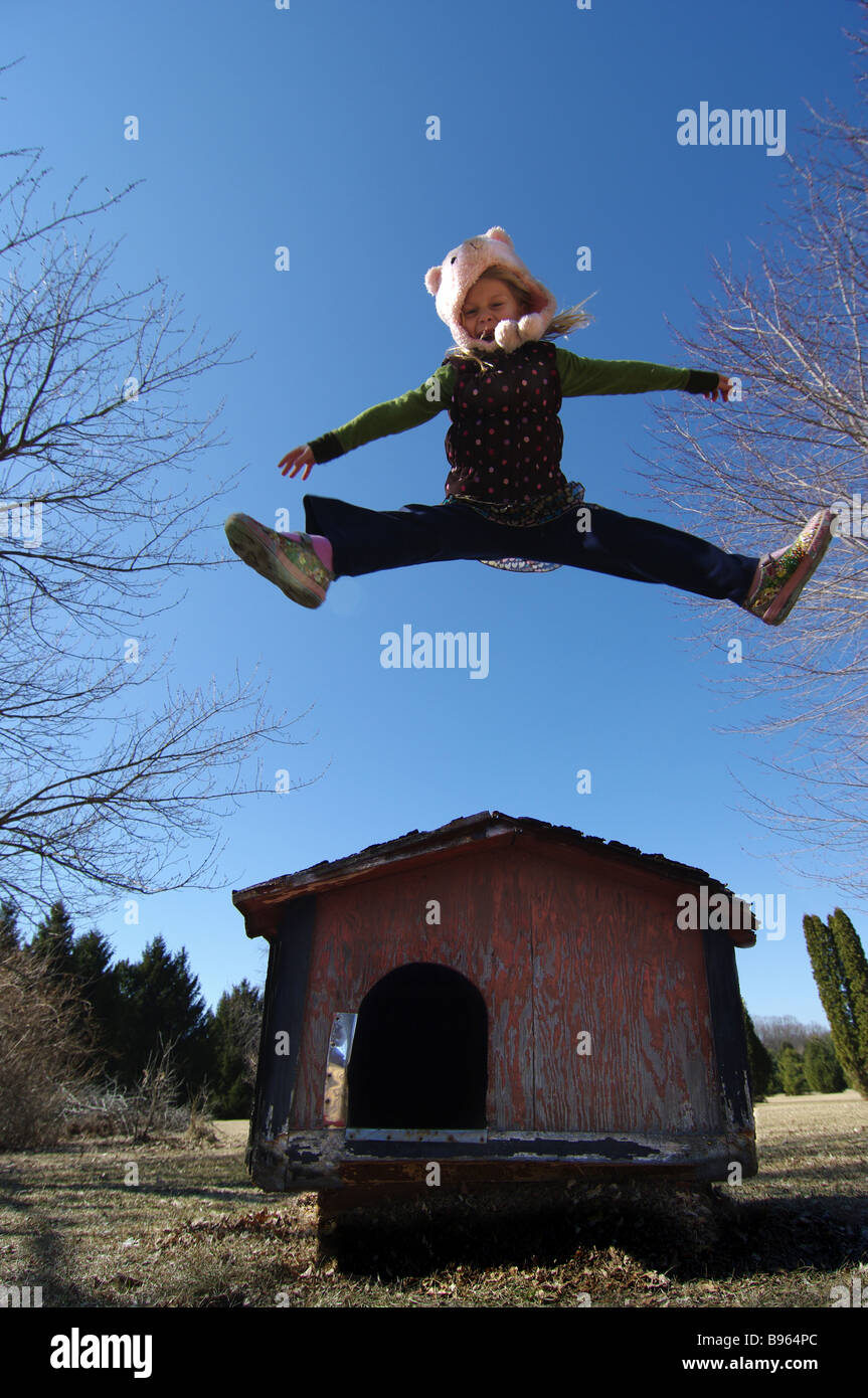 A girl pretends she's an animal as she plays outside in a dog house. Stock Photo