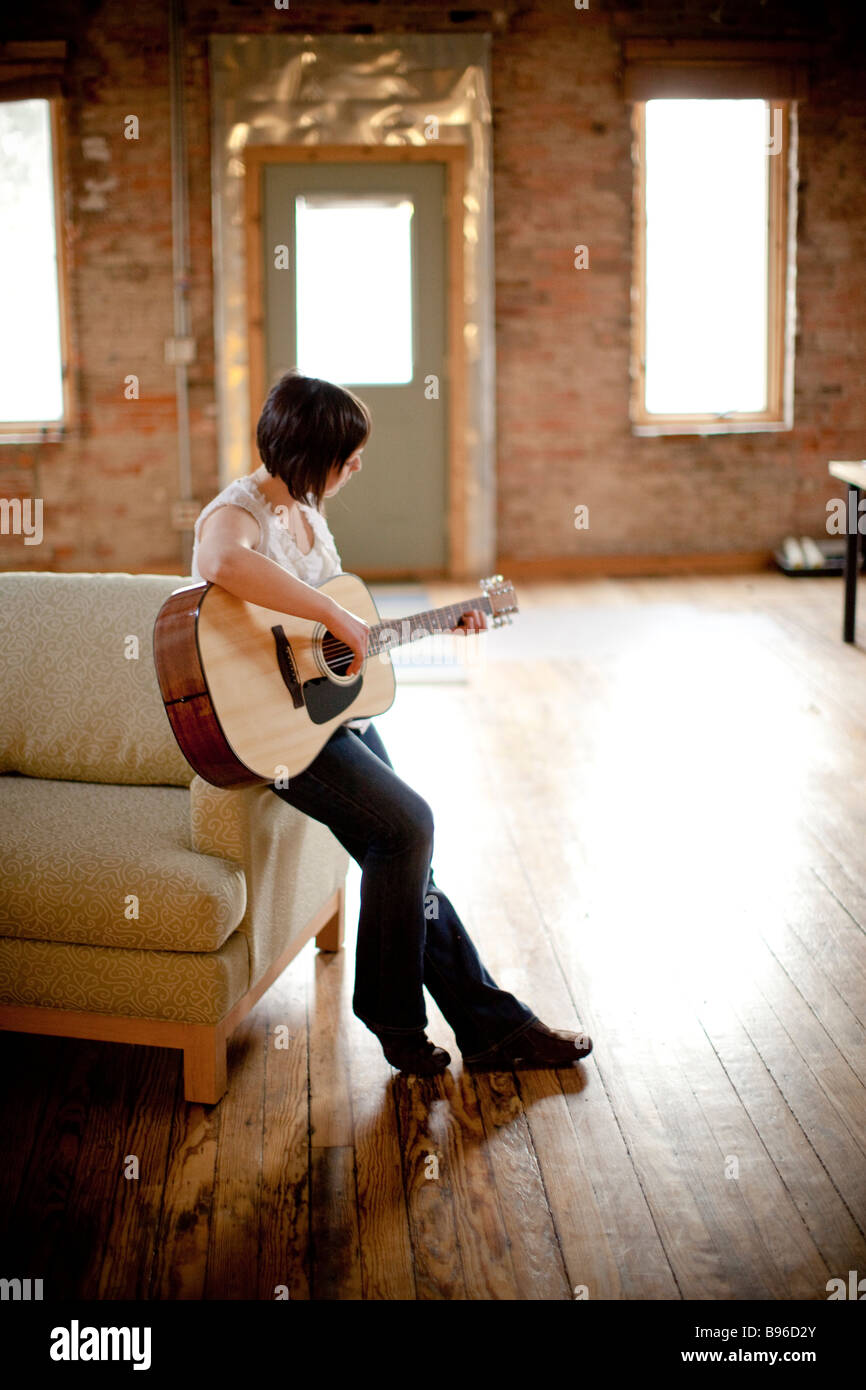 Young woman playing guitar in urban space Stock Photo